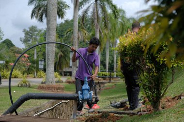 Muadzam Şah, Malezya - 1 Eylül 2021: İki işçi ana drenaja kask veya bot gibi güvenlik ekipmanları olmadan yeni HDPE boruları kuruyor.