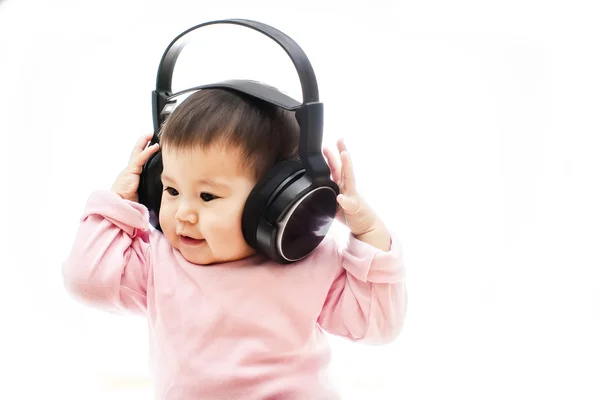 Uma pequena menina feliz ouve música de rádio com fone de ouvido com as mãos — Fotografia de Stock