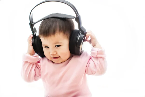 Uma pequena menina feliz ouve música de rádio com fone de ouvido com as mãos — Fotografia de Stock