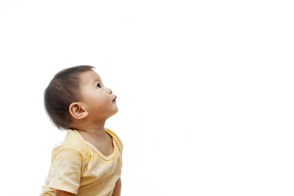 A baby girl looks up with yellow clothes, not looking camera — Stock Photo, Image