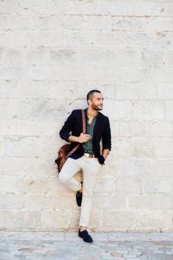 Şık sakallı adam beyaz duvarına karşı duran ve seyir bir