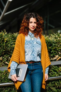 Metal korkuluk yakınındaki dizüstü bilgisayar konumu olan kırmızı saçlı kadın