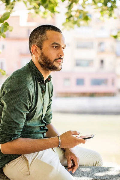 Seitenansicht eines bärtigen Mannes, der über sein Telefon chattet — Stockfoto