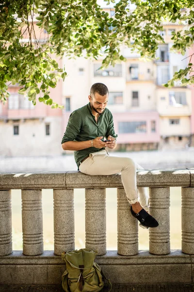 Side view of bearded man sitting on fence under trees — Stock Photo, Image