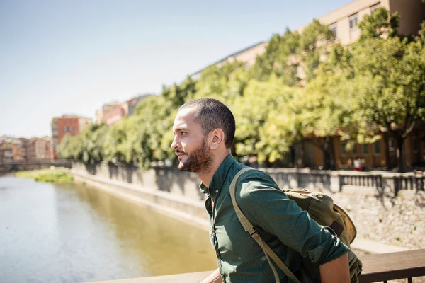 Bonito homem barbudo caminhando na ponte e olhando para longe — Fotografia de Stock