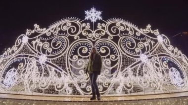 Güzel kız yılbaşında Noel Aydınlatmasının önünde duruyor