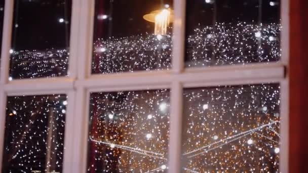 Nieuwjaar prachtige slinger decoratie wordt weerspiegeld in het raam buiten. — Stockvideo