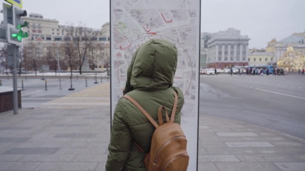 Κορίτσι τουρίστρια στο κέντρο της πόλης κοιτάζει σε ένα χάρτη. Πίσω όψη από πίσω — Αρχείο Βίντεο