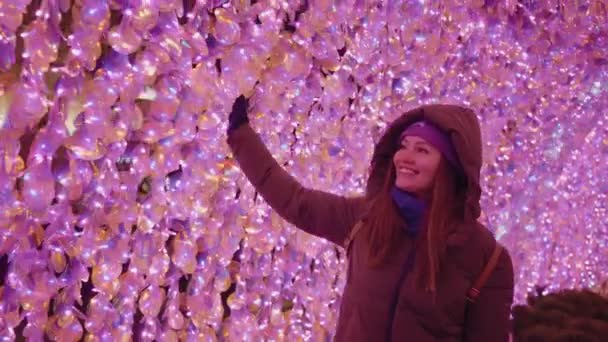 A girl with a smile walks along the Christmas lights. new year mood. — Stock Video
