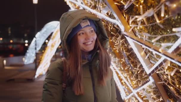 Bella ragazza cammina con i capelli lunghi scuri lungo la decorazione di Natale steret — Video Stock