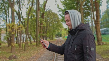 Nomofobi - cep telefonu kullanan insanlar. Cep telefonu fobisi. Genç adam parktaki bir video görüşmesinde konuşuyor. Akıllı telefonsuz bir hayat, bir köle ile iletişim kurmak mümkün değil.