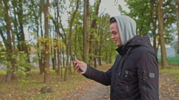 Νομοφοβία - Οι άνθρωποι που χρησιμοποιούν το κινητό τηλέφωνο. Μη-κινητή-τηλέφωνο φοβία. Ο νεαρός μιλάει σε μια βιντεοκλήση στο δρόμο στο πάρκο. Ζωή χωρίς smartphone δεν είναι δυνατή, επικοινωνία με έναν σκλάβο — Φωτογραφία Αρχείου
