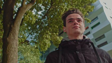 Sokakta yürürken kablosuz kulaklık kullanan genç bir adam. Genç adam, modern kablosuz kulaklık takıyor. Genç bir adamın portresi..