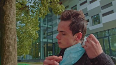 Koronavirüs salgınının sonunda, neşeli beyaz adam koruyucu yüz maskesini çıkartıyor,... yavaş hareket ediyor, kapanıyor, PORTRAIT, Caddenin ortasında dikilen adam cerrahi maskesini çıkarıyor.