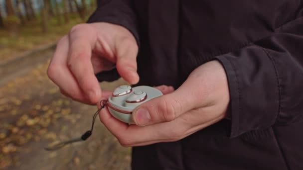 Primer plano de los auriculares inalámbricos en las manos. Acciones. El hombre pasa un par de auriculares inalámbricos blancos. Elegantes auriculares Bluetooth modernos. joven sosteniendo auriculares modernos en la calle. — Vídeo de stock