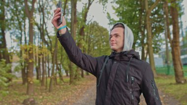 Nomofobi - cep telefonu kullanan insanlar. Cep telefonu fobisi. Genç adam parktaki bir video görüşmesinde konuşuyor. Akıllı telefonsuz bir hayat, bir köle ile iletişim kurmak mümkün değil.