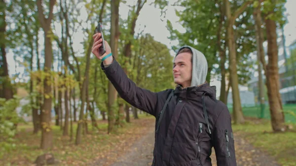 Nomofobie - Mensen die de mobiele telefoon gebruiken. Geen mobiele telefoon fobie. Jongeman aan het praten op een videogesprek in het park. Leven zonder smartphone is niet mogelijk, communicatie met een slaaf — Stockfoto