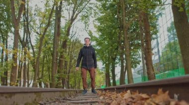 Oyuncu, mutlu bir genç, öğrenci, başarıya sevinir. Genç bir adam parkta zıplıyor ve güzel bir günbatımının arka planına mutlulukla zıplıyor. Ağır çekim. Ön tarafta.