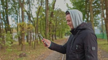 Nomofobi - cep telefonu kullanan insanlar. Cep telefonu fobisi. Genç adam parktaki bir video görüşmesinde konuşuyor. Akıllı telefonsuz bir hayat, bir köle ile iletişim kurmak mümkün değil.