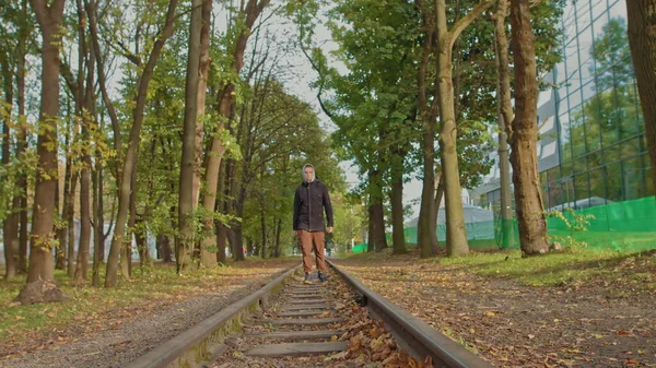 En ung kille flyttar tryggt till kameran i parken på banan, en stilfullt klädd tonåring. — Stockfoto