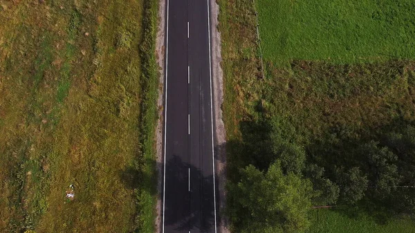 Veduta aerea drone di ampia strada aperta vuota in profondità tra foresta selvaggia con dolci colline e montagne — Foto Stock
