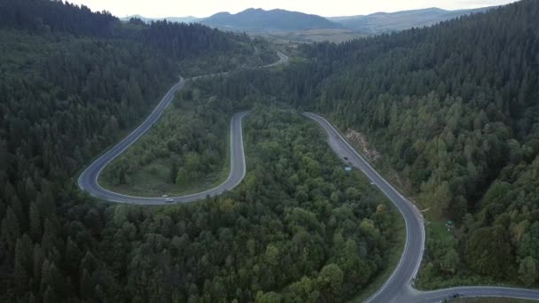 Nagranie B Rolka drona z widokiem z lotu ptaka nad krętą drogą krajobrazową. samochód jadący krętą drogą. Wideo z dronem 4K. droga kręta w górach w letni słoneczny dzień. obwody — Wideo stockowe