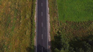 Uçan drone manzarası geniş, boş bir yol vahşi ormanın derinliklerinde, tepeler ve dağlarla birlikte.