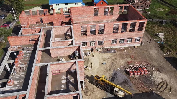 Vista superior dos guindastes de construção e do processo de construção de uma nova escola na Europa. Construção de novos edifícios para habitação e escritório, fotografia aérea no centro. — Fotografia de Stock