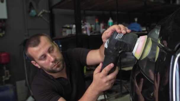 Polishing car headlights. A man uses a special device to restore the headlights of an expensive black car.Detailing, cleaning the surface of the car from contamination with further polishing to an — Stock Video