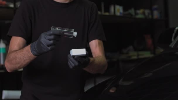 Dettagli dell'auto: l'uomo applica un rivestimento nano protettivo o cera sull'auto nera. Coprire il cofano dell'auto con uno smalto di vetro liquido — Video Stock