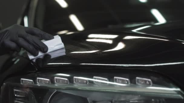 Bil detalj - Man tillämpar nano skyddande beläggning eller vax på svart bil. Täcka bilhättan med flytande glaspolning — Stockvideo