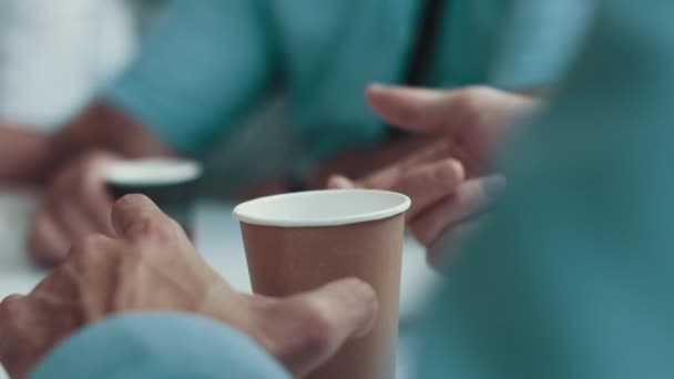 Primer plano de café en la mesa y las manos de los empresarios. Un hombre tomando café en una reunión con clientes. Agradable reunión de empleados con una taza de café. — Vídeo de stock
