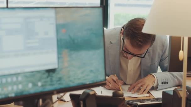 Joven empresario serio revisando la correspondencia de papeleo corporativo sentado en el escritorio de la oficina en casa. Empresario masculino leyendo documentos, analizando documentos financieros, preparando informe de auditoría en el lugar de trabajo. — Vídeos de Stock