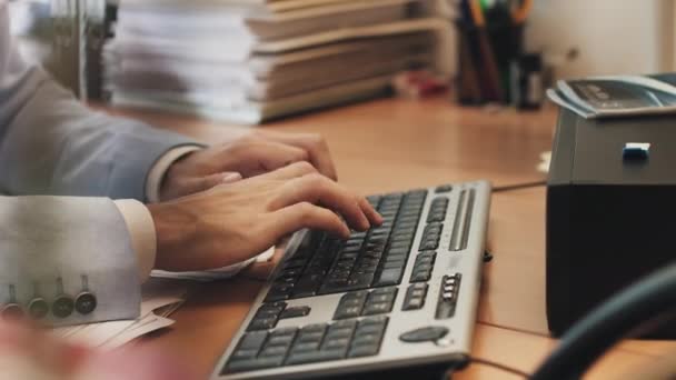 Jeune homme travaille à un ordinateur portable assis à table dans le bureau à la maison. à la recherche des informations nécessaires, des nœuds et des sourires. commencer à taper sur le clavier — Video