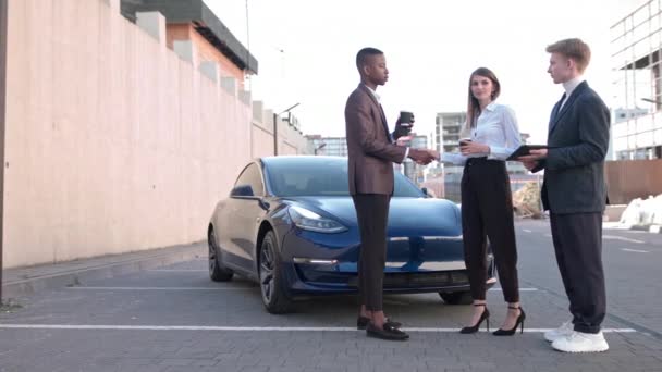 Bel homme afro-américain et belle femme européenne dans les vêtements formels parler avec le concessionnaire de voitures à propos de l'achat d'une nouvelle voiture. Business, achat, vente et concept de personnes. En plein air. Mouvement lent — Video