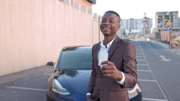Close Up sebevědomý africký Američan koupit nové auto. Veselý černý podnikatel drží moderní elektronický klíč od auta. Portrét úspěšného muže, který se blíží svému cíli a kupuje elektrické auto, aby zachránil — Stock video