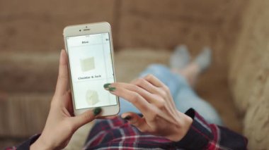 Evdeki Kadın Oturma Odasında Kanepede Uzanıyor İnternet 'ten Akıllı Telefon Alıyor. Çevrimiçi bir dükkanda akıllı telefon kullanarak peynir siparişi veren bir kadın. Kadın Bakkalda Çevrimiçi Peynir Seçiyor