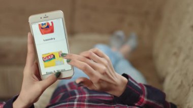 Evdeki Kadın Oturma Odasında Kanepede Uzanıyor İnternet 'ten Akıllı Telefon Alıyor. Çevrimiçi bir mağazada akıllı telefon kullanan bir kadın eve sipariş veriyor. Market Online Mağazasında Kadın Seçmeleri. POV