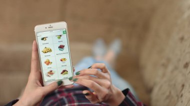 Evdeki Kadın Oturma Odasında Kanepede Uzanıyor İnternet 'ten Akıllı Telefon Alıyor. Kadın akıllı telefon kullanarak çevrimiçi dükkanda meyve siparişi veriyor. Kadın Market İnternetten Meyve Seçiyor. POV