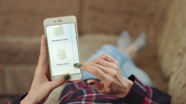 Evdeki Kadın Oturma Odasında Kanepede Uzanıyor İnternet 'ten Akıllı Telefon Alıyor. Çevrimiçi bir dükkanda akıllı telefon kullanarak peynir siparişi veren bir kadın. Kadın Bakkalda Çevrimiçi Peynir Seçiyor