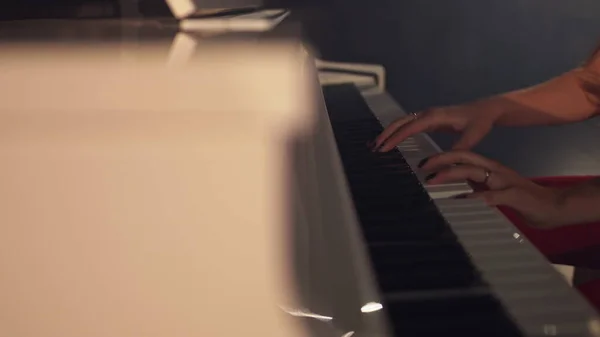 Жінка-піаністка грає ніжну класичну музику на красивому піаніно з крупним планом у повільному русі. Клавіші для фортепіано крупним планом в темних тонах. Студент тренується грати на піаніно — стокове фото