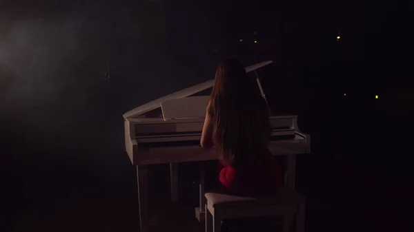 4K filmato di pianista femminile suona in bellissimo pianoforte a coda sul palco in concerto. Una donna suona il pianoforte nella sala da concerto. Palcoscenico luce e nebbia leggera sullo sfondo — Foto Stock