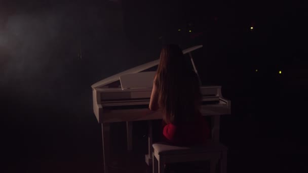 音乐会舞台上美丽的大钢琴中女钢琴家的4K镜头。一个女人在音乐厅里弹钢琴.背景上的舞台灯光和薄雾 — 图库视频影像