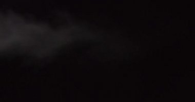 Atmosferik duman 4K sis etkisi. Siyah arka planda ağır çekimde duman. Beyaz duman siyah arkaplana karşı uzayda yavaşça süzülüyor