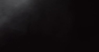 Atmosferik duman 4K sis etkisi. Siyah arka planda ağır çekimde duman. Beyaz duman siyah arkaplana karşı uzayda yavaşça süzülüyor