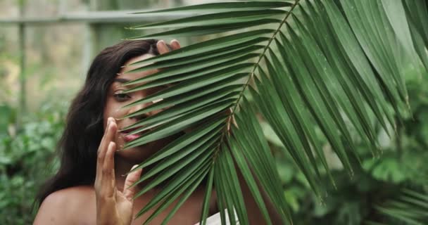 Portret van jonge en mooie vrouw Afro-Amerikaanse met een perfecte gladde huid in tropische bladeren.Concept van natuurlijke cosmetica en huidverzorging. opname op RAW camera met 12bit kleurdiepte Natuurlijke cosmetische — Stockvideo
