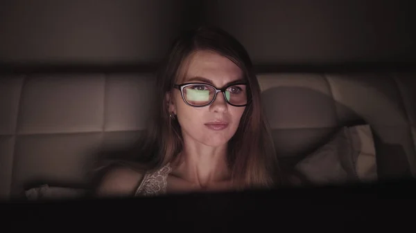 Atractiva joven mujer de negocios que trabaja por la noche a través de la computadora en la oficina con, primer plano de la chica estudiante hipster navegar por Internet, mirando el monitor de la computadora moderna, se centran en las gafas — Foto de Stock