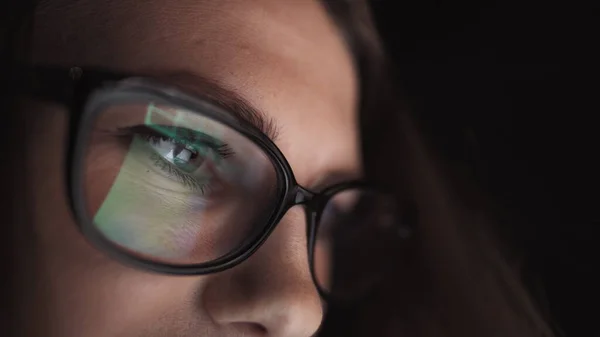 Attractive young businesswoman working at night via computer at office with, closeup of hipster student girl browsing the internet, looking at monitor of modern computer, focus on the glasses — Stock Photo, Image