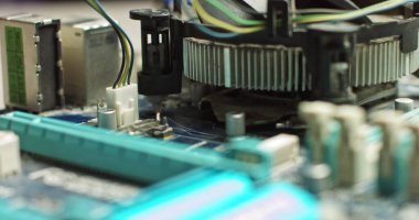 Fişi ana karta bağlayan sihirbaz işlemciyi soğutmaya bağlıyor. Bilgisayar panolarının onarımı ve bakımı. Modern Elektronik İmalat Fabrikası Tasarım Mühendisi Mikroçipi. Yeni