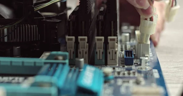 Conectando cables en una computadora. Componentes dentro de la unidad del sistema. Tarjeta de vídeo y RAM en la placa base. Conectando un chip en un portátil. Conector con cables. Técnico maestro monta una computadora —  Fotos de Stock